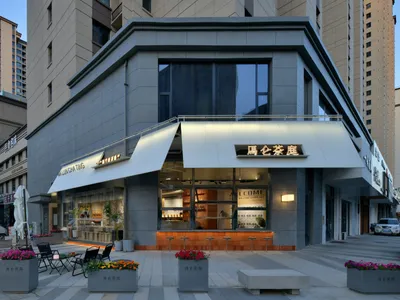A modern Asian restaurant with a large window, gray and white elements, chairs, and potted plants, creating a clean and inviting atmosphere