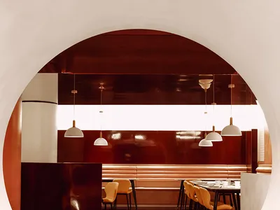 A restaurant with a circular design featuring tables and chairs arranged to create a cozy atmosphere, with a large table at the center and smaller ones nearby