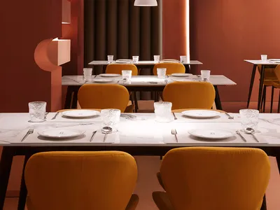 Warm and inviting dining space with a long table, yellow chairs, and soft lighting, surrounded by wood elements