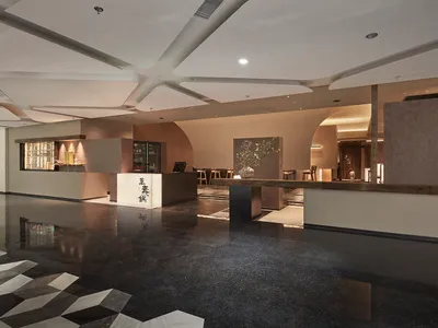 A hotel lobby with a large open area, a counter, chairs, and a potted plant, creating a welcoming atmosphere for guests