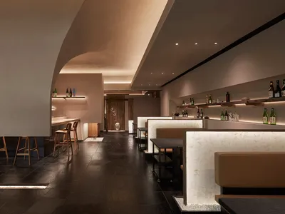 現代餐廳內部，高挑天花板、多張餐桌與現代牆面設計，搭配酒瓶與舒適座位區歡迎賓客