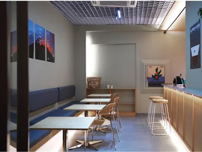 空蕩蕩的餐廳內部，現代設計、白牆壁與柔和燈光，寬敞餐區擺放數張桌椅