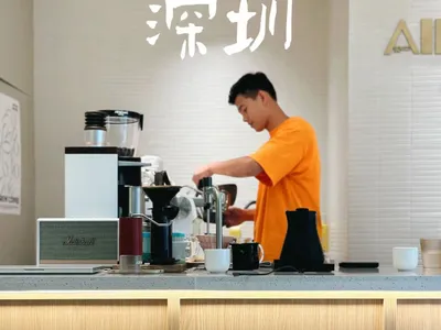 一名男子在廚房使用咖啡機、杯子與碗具準備咖啡，周圍瀰漫著悠閒氛圍