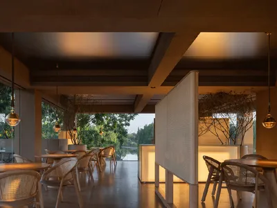 Cozy restaurant interior with wooden tables and chairs, potted plants, and a modern design