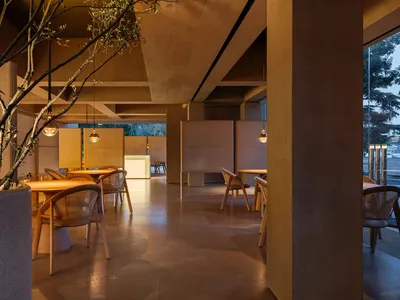 A well-lit dining area with multiple tables and chairs, surrounded by brown walls, creating a warm atmosphere