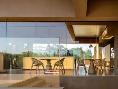 A warm and inviting living room with a large window, chairs, and a dining table, surrounded by natural light