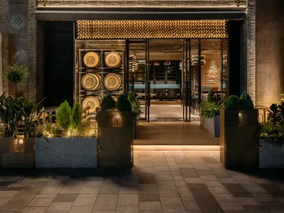 A modern Asian restaurant with a spacious interior, bar area, and potted plants, creating a welcoming atmosphere