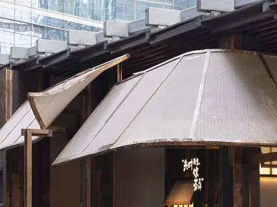A warm and inviting Asian restaurant with wooden walls, stone countertops, and umbrella-like structures providing shade