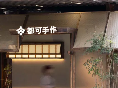 A woman walks through the entrance of an Asian restaurant with a warm and inviting atmosphere, surrounded by wooden elements and potted plants