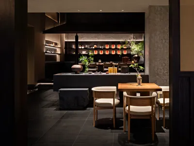 A cozy restaurant dining area with chairs, tables, potted plants, and decorative elements on the walls