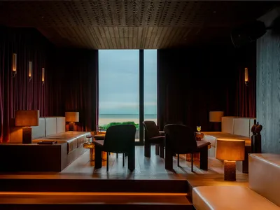 Sophisticated living space with ocean view, chairs, and dining table, surrounded by natural light and tranquil atmosphere