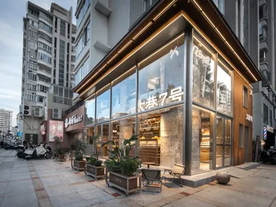 Spacious modern restaurant with glass doors, wooden and metal elements, potted plants, and a comfortable atmosphere