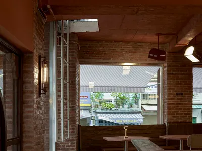 Modern restaurant interior with brick walls, a wooden countertop, and dining tables near windows, featuring a warm and inviting atmosphere
