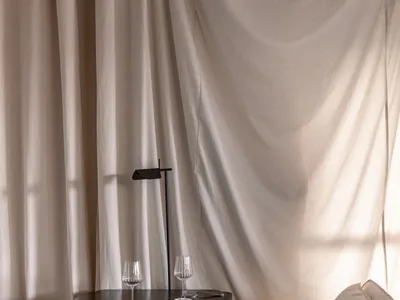 A living area with a couch next to a window, wine glasses on a table, and elegant curtains creating a comfortable and cozy atmosphere