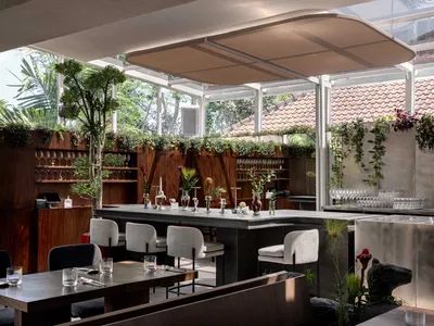 Elegant dining space with a large bar, multiple chairs, wine glasses, cups, and vases, creating a sophisticated atmosphere for socializing and enjoying drinks
