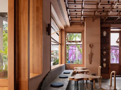 Warm and inviting restaurant interior with wooden walls and floors, natural light from windows, and seating areas