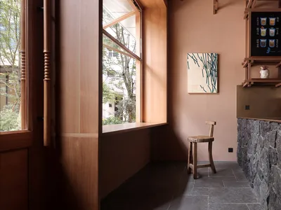 A warm and inviting living space with a brown-colored room, a dining table, two chairs, and large windows allowing natural light to enter