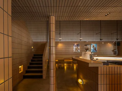 Warm and inviting restaurant interior with a dining area, bar counter, and patrons enjoying their meal