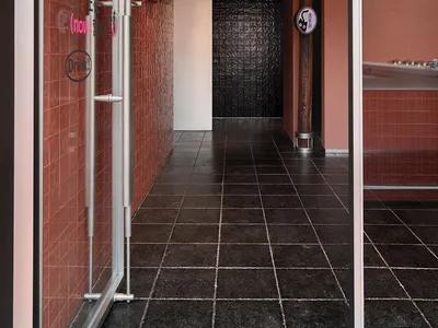 A modern hotel hallway with red brick walls, black tile floor, and two doors on either side