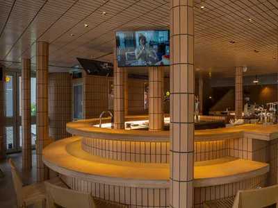 Modern restaurant bar with a TV mounted above it, featuring two chairs and a comfortable atmosphere