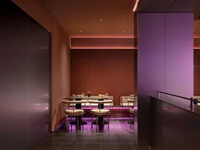 擁有紫色牆面與地板的大型餐廳區域，配有多張桌椅、裝飾花瓶，營造舒適氛圍