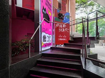 Modern hotel lobby with pink walls, a staircase, and signs including one reading Golden Cat, with a cat present in the scene