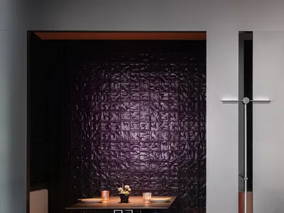 A cozy dining area in a restaurant with two tables, purple tile walls, and comfortable seating