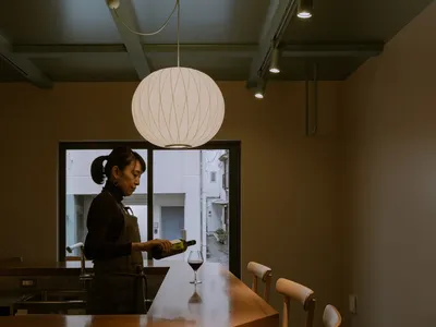 一位女性站在木質餐桌旁，周圍環繞著椅子，營造出輕鬆舒適的餐廳氛圍