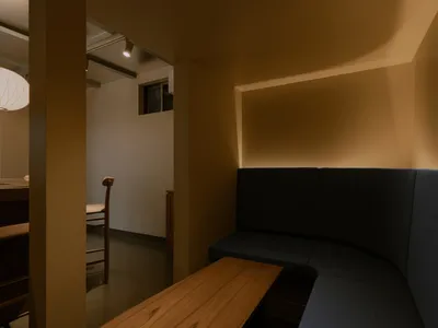 Cozy living and dining space with yellow walls, a window, and natural light, featuring a bench, chair, and inviting atmosphere
