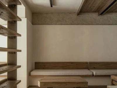 Empty living space with wooden floors and walls, featuring two benches, a dining table, and chairs in a minimalist and clean atmosphere
