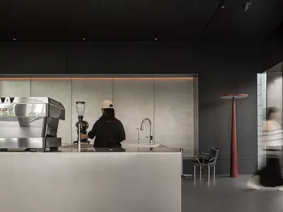 A modern restaurant interior with a counter featuring a metallic finish, black and white walls, and two people in the scene