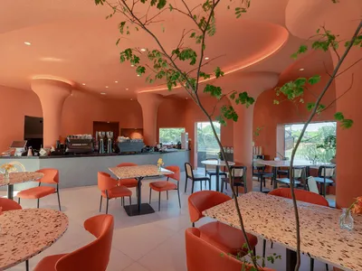 Warm and inviting restaurant interior with orange walls, tables, chairs, and cups, creating a lively atmosphere