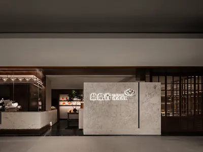 A modern Asian restaurant with a marble countertop, large window, and natural light, featuring potted plants, vases, and decorative elements