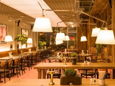 燈光柔和的餐廳內部，配有木桌椅、盆栽與吊燈