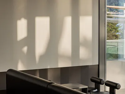 Comfortable living space with two black couches, three chairs, and natural light from a window