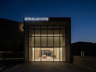 A warm and inviting coffee shop with a stone facade, glass door, and comfortable seating areas, perfect for socializing and relaxation