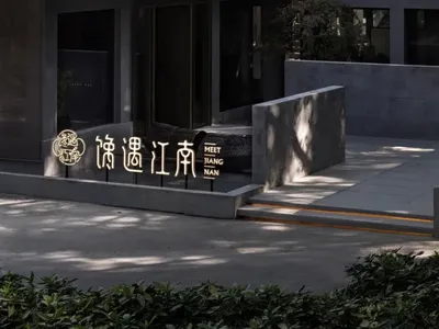 A modern Asian restaurant with a large stone wall, seating areas, potted plants, and a well-designed atmosphere