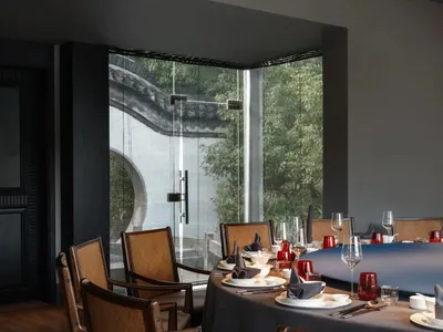 Elegant Asian restaurant interior with a large dining table set with various items and vases, surrounded by chairs