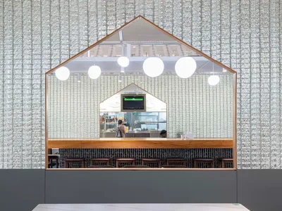 Modern restaurant bar with wood accents, TVs, and comfortable seating, well-lit for a welcoming atmosphere