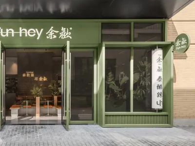 An inviting Asian restaurant with green walls, wooden furniture, and potted plants, creating a comfortable dining atmosphere