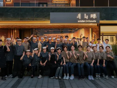 A group of people gathered in front of an Asian-themed restaurant, smiling and posing for a photo