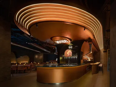 A modern restaurant interior with a golden bar counter, comfortable seating, and well-lit dining area