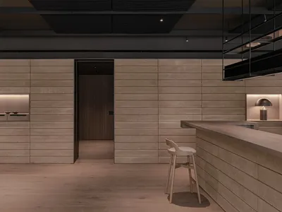 Modern kitchen with wooden walls and floors, a large countertop, and a sink, featuring two chairs in a clean and well-organized space
