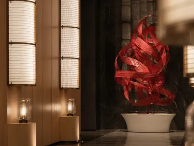 A modern decorative art piece featuring a red ribbon sculpture in a white bowl on a marble countertop, creating an elegant and sophisticated atmosphere