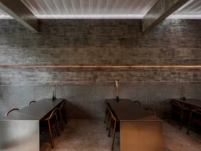Elegant restaurant interior with stone walls, two dining tables, and multiple chairs, creating a sophisticated atmosphere