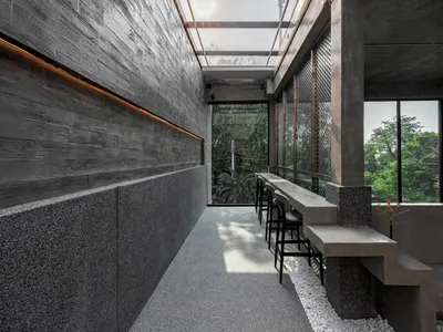 現代餐廳內有大型餐桌、混凝土牆面、玻璃天花板與盆栽植物，營造出適合社交與用餐的溫馨氛圍