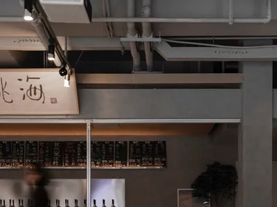 A modern Asian restaurant with a bar area and dining tables, featuring bottles and an inviting atmosphere
