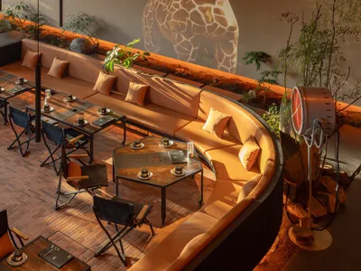 A modern restaurant interior with multiple tables, couches, and decorative items creating a cozy atmosphere