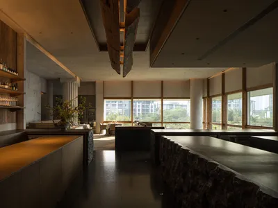 現代廚房配大型餐桌、黑色檯面、家電與盆栽，營造當代溫馨氛圍