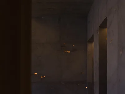 Dark living room with a couch in the corner, two benches, and dim lighting, featuring concrete walls